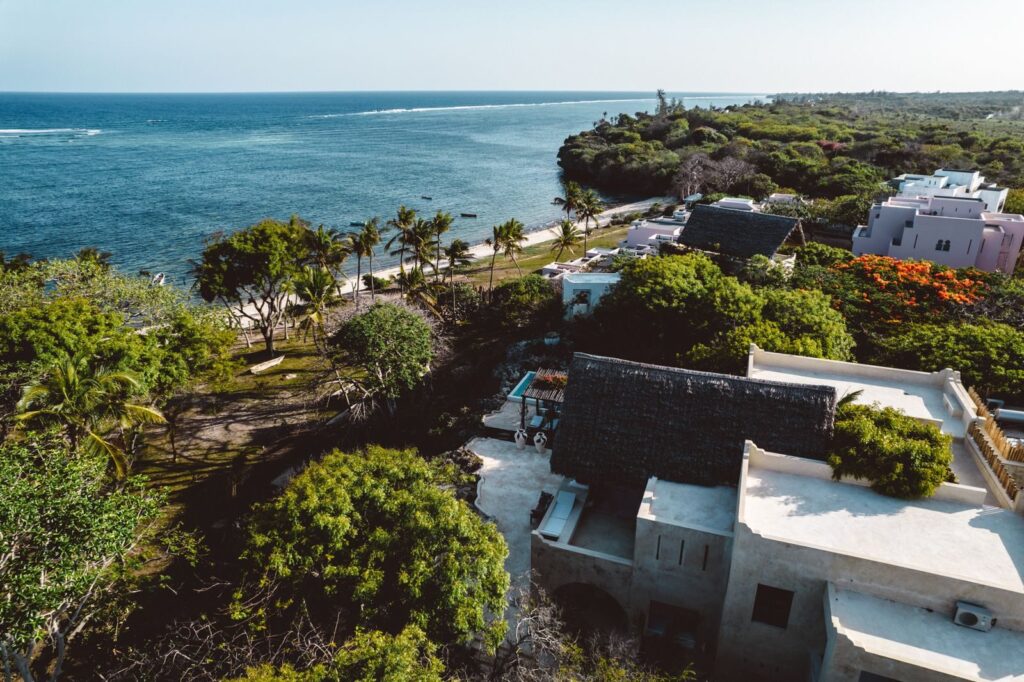 A scenic aerial view of lush trees and coastal homes along the Kenyan shoreline.